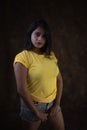 Studio portrait of a beautiful and young Indian Bengali female model in yellow tee shirt and jeans hot pat Royalty Free Stock Photo