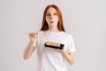 Studio portrait of beautiful young woman eating delicious sushi rolls with chopsticks looking at camera standing on Royalty Free Stock Photo