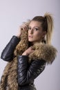 Studio portrait of beauty blond woman standing in black clothes and black leather jacket with fur collar Royalty Free Stock Photo