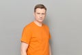 Portrait of serious blond mature man wearing bright orange T-shirt Royalty Free Stock Photo