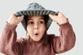 Studio portrait of Caucasian little girl in the winter warm gray hat, has surprised face and wearing sweater isolated on a white Royalty Free Stock Photo