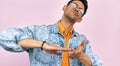 Studio portrait of Caucasian young man wearing spectacles, yellow t-shirt and denim jacket throwing away money. Male gesticulating Royalty Free Stock Photo