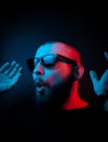 Studio portrait of a charismatic guy in neon style. Stock photo of a bearded guy surprised by surprise