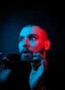 Studio portrait of a charismatic guy in neon style. Stock photo of a bearded guy surprised by surprise
