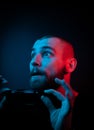 Studio portrait of a charismatic guy in neon style. Stock photo of a bearded guy surprised by surprise