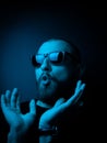 Studio portrait of a charismatic guy in neon style. Stock photo of a bearded guy surprised by surprise