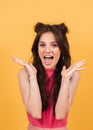 Studio portrait of a cheerful emotional girl on a bright yellow background.