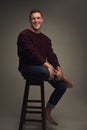 Always ready talk. Studio portrait of a cheerful young man seated against a grey background while looking at the camera. Royalty Free Stock Photo