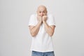 Studio portrait of cute bald caucasian male biting fists and lifting eyebrows, expressing fright while standing against Royalty Free Stock Photo