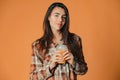 Cute caucasian young brunette girl holding plastic cup of orange juice on orange background Royalty Free Stock Photo