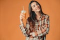 Cute caucasian young brunette girl holding plastic cup of orange juice on orange background Royalty Free Stock Photo