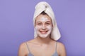 Studio portrait of delighted magnetic young female looking directly at camera, applying mask, caring about skin condition, smiling