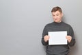 Portrait of disappointed man holding white blank paper sheet in hands