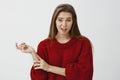 Studio portrait of doubtful unimpressed cute girlfriend in trendy loose sweater, gesturing with head and lifting one