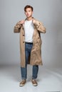 A studio portrait of an East Asian man posing in a coat