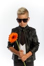 Studio portrait of fashionable blond caucasian boy with single gerbera flower, white background, copy space Royalty Free Stock Photo