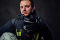 Firefighter dressed in uniform holds safety helmet.