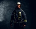 Portrait of firefighter dressed in uniform and safety helmet looking sideways with a confident look