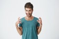 Studio portrait of funny expressive spanish guy in blue t-shirt, playing fool showing tongue and teeth, having fun