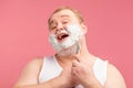 Happy plump man with shaving foam on his face and razor isolated on pink Royalty Free Stock Photo