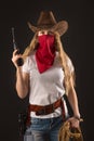 Portrait of a girl in a cowboy hat, with a red bandana, a gun and a rope