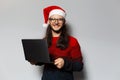 Studio portrait of handsome smiling guy, holding laptop in hands. Wearing Santa Claus hat. Christmas concept. White background Royalty Free Stock Photo