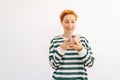 Studio portrait of happy attractive young woman typing online message using phone standing on white isolated background Royalty Free Stock Photo