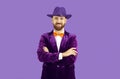 Studio portrait of happy bearded man in purple hat, velvet suit and orange bow tie Royalty Free Stock Photo