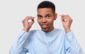 Studio portrait of happy dark-skinned man touching earphones, listens the music. Indoor shot of African American young male wears Royalty Free Stock Photo