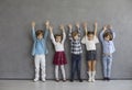 Studio group portrait of happy little children standing together and raising hands Royalty Free Stock Photo