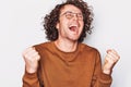 Studio portrait of happy successful male student or business man with curly hair wearing round eyeglasses, screaming with winning Royalty Free Stock Photo