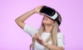 Studio portrait of happy woman using VR headset, looking up, trying to touch objects in virtual reality, isolated on pink Royalty Free Stock Photo