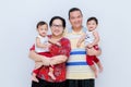 Studio portrait of happy young family with little children. Parents At Home Cuddling Twin Baby Daughters In Nursery .