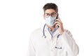 Studio portrait of male doctor talking with sombody on his mobile phone while standing at isolated white background Royalty Free Stock Photo