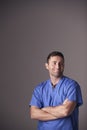 Studio Portrait Of Male Nurse Wearing Scrubs Standing Against Grey Background