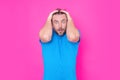 Studio portrait of a man shocked. Surprised man in blue t-shirt shouting wow, omg, isolated on pink background. Shock Royalty Free Stock Photo