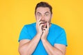 Studio portrait of a man shocked. Surprised man in blue t-shirt shouting wow, omg, isolated on yellow background. Shock Royalty Free Stock Photo