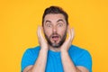 Studio portrait of a man shocked. Surprised man in blue t-shirt shouting wow, omg, isolated on yellow background. Shock Royalty Free Stock Photo