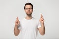 Studio portrait millennial guy in eyeglasses crossing fingers.