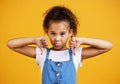 Studio portrait mixed race girl giving thumbs .down isolated against a yellow background. Cute hispanic child posing Royalty Free Stock Photo