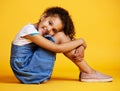 Studio portrait mixed race girl looking sitting alone  against a yellow background. Cute hispanic child posing Royalty Free Stock Photo