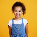 Studio portrait mixed race girl looking standing alone isolated against a yellow background. Cute hispanic child posing Royalty Free Stock Photo