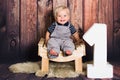 Studio portrait of one year old baby boy sitting on chair in front of wooden background. One year concept with copy space Royalty Free Stock Photo