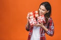 Studio portrait of smiling young beautiful woman holds red gift boxes. Isolated against orange background Royalty Free Stock Photo