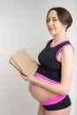 Studio portrait of young adult pregnant woman holding stack of books, preparing for babybirth concept, white background Royalty Free Stock Photo