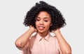 Studio portrait of pretty African American young woman, wears casual beige shirt, straightens her afro curly hair. Afro pretty Royalty Free Stock Photo