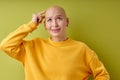 Studio portrait of pretty bald woman pondering over something touching head Royalty Free Stock Photo