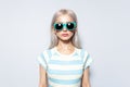 Studio portrait of pretty blonde girl in striped shirt with sunglasses on white. Royalty Free Stock Photo