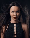 Studio portrait of pretty brunette woman with long hair flying on black background. Royalty Free Stock Photo