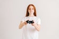 Studio portrait of pretty young woman playing video game with controller looking at camera on white  background. Royalty Free Stock Photo